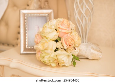 Bridal Bouquet Lying On A Bedstand Near A Photo In A Frame