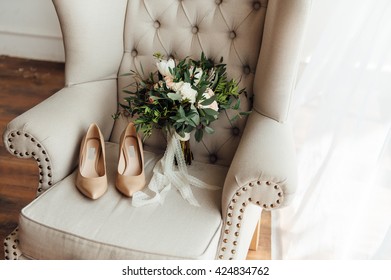 bridal bouquet of peones, wedding flowers for the ceremony on the chair in a hotel room with white shoes.