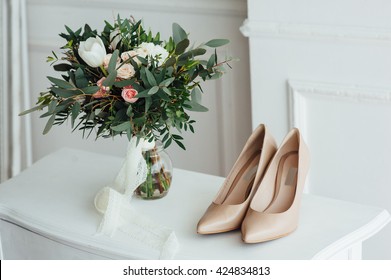 bridal bouquet of peones, wedding flowers for the ceremony on the chair in a hotel room with white shoes.