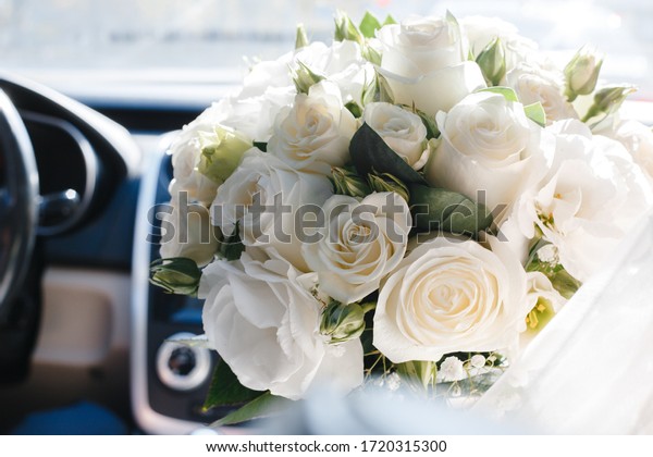 Bridal bouquet\
of white roses in a car\
interior