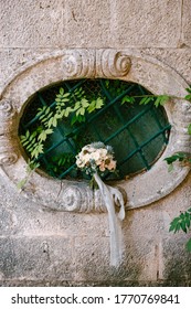 Bridal Bouquet Of White Roses, Eucalyptus Tree Branches, Sempervivum, Scabiosa And Blue Ribbons On The Oval Window Of An Ancient House