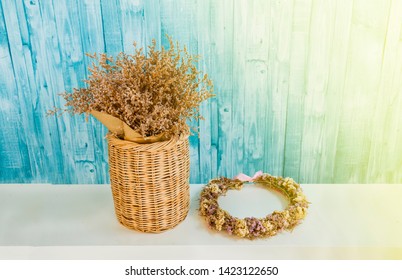 A Bridal Flower Crown Near Wooden Basket With Dried Flowers On Blue Background.image