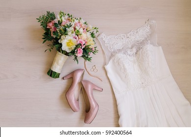 Bridal Morning Details. Wedding Rings, Beautiful Bouquet Of Yellow And Pink Flowers, White Wedding Dress And Leather Shoes.