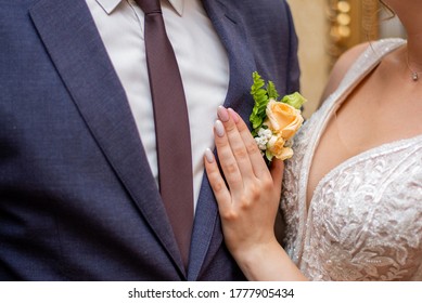 Bride Adjusts Cream Roses Buttonhole To Her Groom