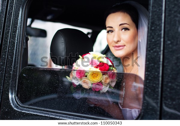 bride with a\
bouquet of roses sitting in the\
car