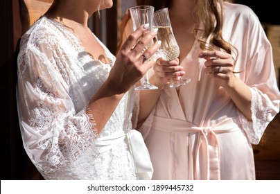 Bride And Bridesmaid Holding Champagne Glasses