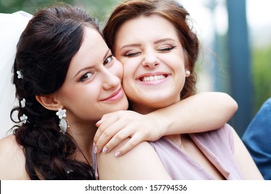 bride and bridesmaid outside happy hug - Powered by Shutterstock