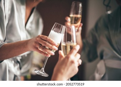 bride with bridesmaids indoors with a ring on her hand holding glasses of champagne in her hands, close-up front view - Powered by Shutterstock