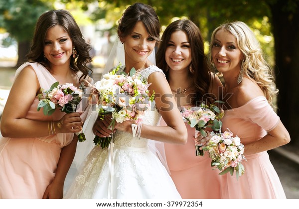 Bride\
with bridesmaids on the park on the wedding\
day