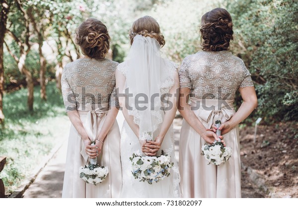 花嫁をポーズをとり 花束を後ろに持つ花嫁 晴れた庭で楽しい女の子を持つ幸せな結婚式の花嫁 の写真素材 今すぐ編集