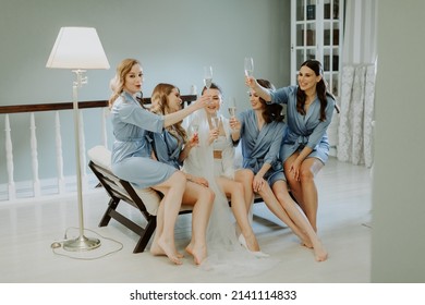 Bride And Bridesmaids Sitting In Silk Robes With Glasses Of Champagne