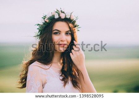 Bride in a chaplet and long gown and beautiful nature behind her