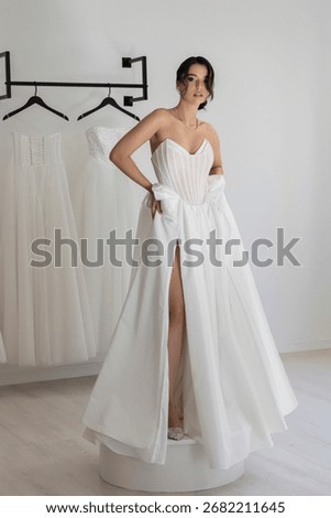 Bride in chic strapless gown with structured corset and high slit posing gracefully indoors