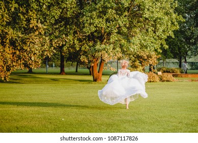 The bride in a chic wedding dress is running along a beautiful lawn. exit ceremony. wedding in the woods