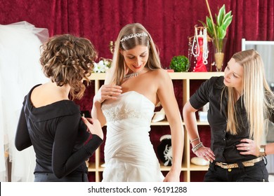 Bride At The Clothes Shop For Wedding Dresses; She Is Choosing A Dress And The Designer Is Assisting Her