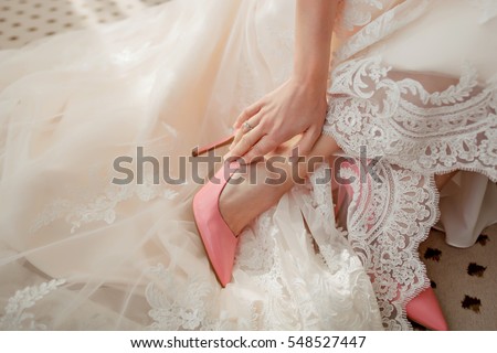 Bride dress shoes. The bride puts on a Shoe. Coral shoes of the bride. Lace wedding dress