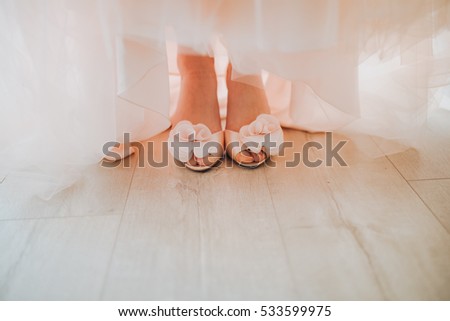 bride in a dress and shoes is standing on wooden floor