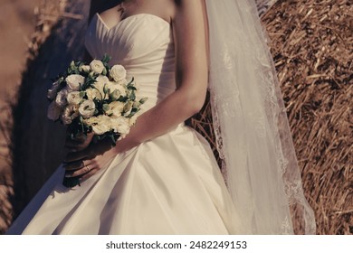 The bride in an elegant wedding dress holds a beautiful bouquet of different flowers and green leaves. Wedding theme.