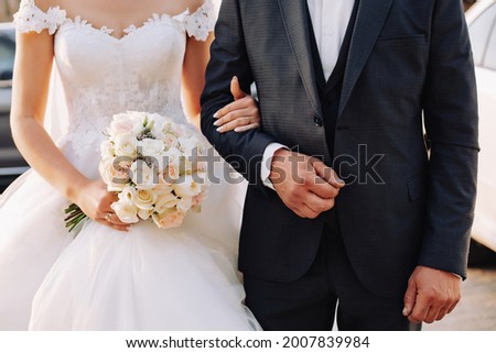 The bride and Father are standing next to each other and a Father holds her Arm. Slim beautiful young bride holding her father's hand before her wedding. Bride and Father Arm in Arm. 