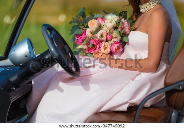 Bride with flowers in a golf\
car