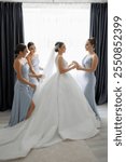 A bride is getting ready for her wedding with her bridesmaids. The bride is wearing a white dress and the bridesmaids are wearing blue dresses