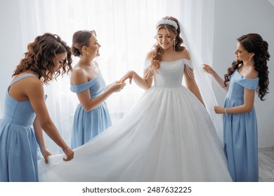 A bride is getting ready for her wedding with her bridesmaids. The bride is wearing a white dress and the bridesmaids are wearing blue dresses - Powered by Shutterstock