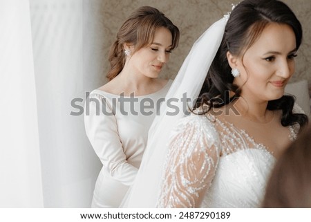 A bride is getting ready for her wedding, with her bridesmaids helping her