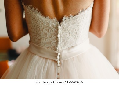 Bride getting ready, they help her by buttoning the buttons on the back of her dress. - Powered by Shutterstock