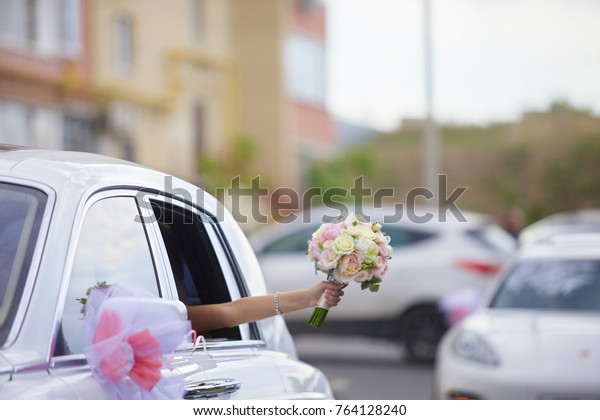 bride girl goes\
to wedding cars and waving with a bouquet out of it. The bride\'s\
bouquet of flowers. Wedding\
day.