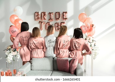 Bride with girlfriends in silk robes at a bachelorette party.