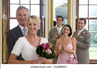 Bride and groom by bridesmaid and ushers clapping, smiling, portrait