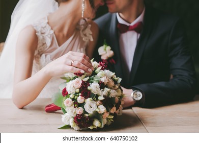 bride and groom in a cafe. wedding bouquet on a wooden table in a restaurant
bride and groom hold each other's hands. Wedding rings. Loving couple in a cafe. hot tea for lovers