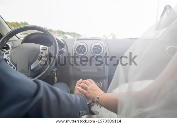 bride and groom in a car - just married. the\
newlyweds are holding hands in a\
car.