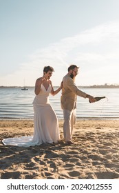 A Bride And Groom Celebrate Their Intimate Beach Wedding By Popping Champagne 