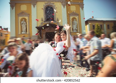 Bride And Groom At Church Door With Rice Confetti Being Thrown