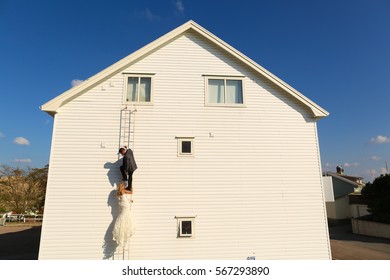 Bride And Groom Climbing On A White House