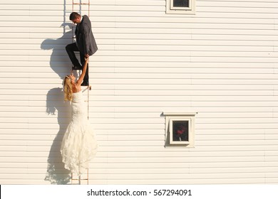 Bride And Groom Climbing On A White House