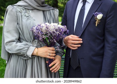 Bride and groom with engagement dresses. Bride is holding bouquet in her hands. Groom is wearing blue suit. Muslim engagement concept.
