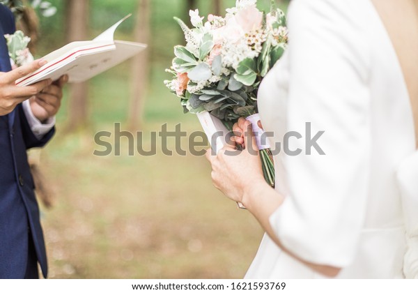 Bride and groom exchanging wedding vows wedding\
ceremony in nature.