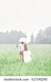 The Bride And Groom Go Under Rain. Rainy Wedding Day.