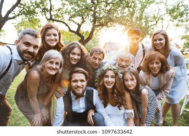 Bride, Groom, Guests Posing For The Photo At Wedding Reception Outside In The Backyard.