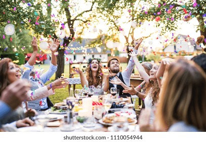 Bride and groom with guests at wedding reception outside in the backyard.