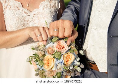 bride and groom hands with weddingrings showing power fist