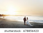 Bride and groom hold each other hands posing on the beach