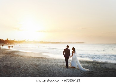 Bride and groom hold each other hands posing on the beach - Powered by Shutterstock