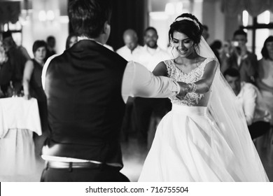 Bride and groom hold each other hands dancing in the hall