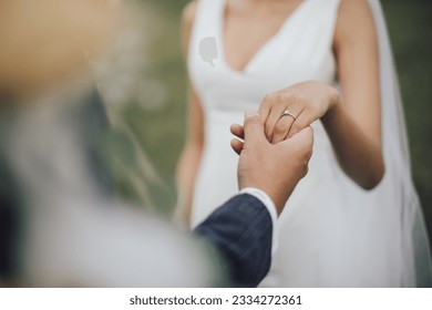 The bride and groom hold hands on their wedding day and put their rings on each other in love on a sunny day. and the orange sunlight shining through the hair - Powered by Shutterstock