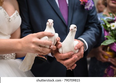 Bride and groom hold white doves