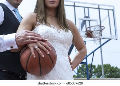 Bride And Groom Holding A Basketball With Basketball net In Background