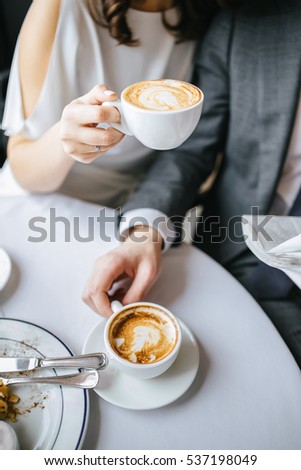 bride and groom holding a cup of coffee in their hands
